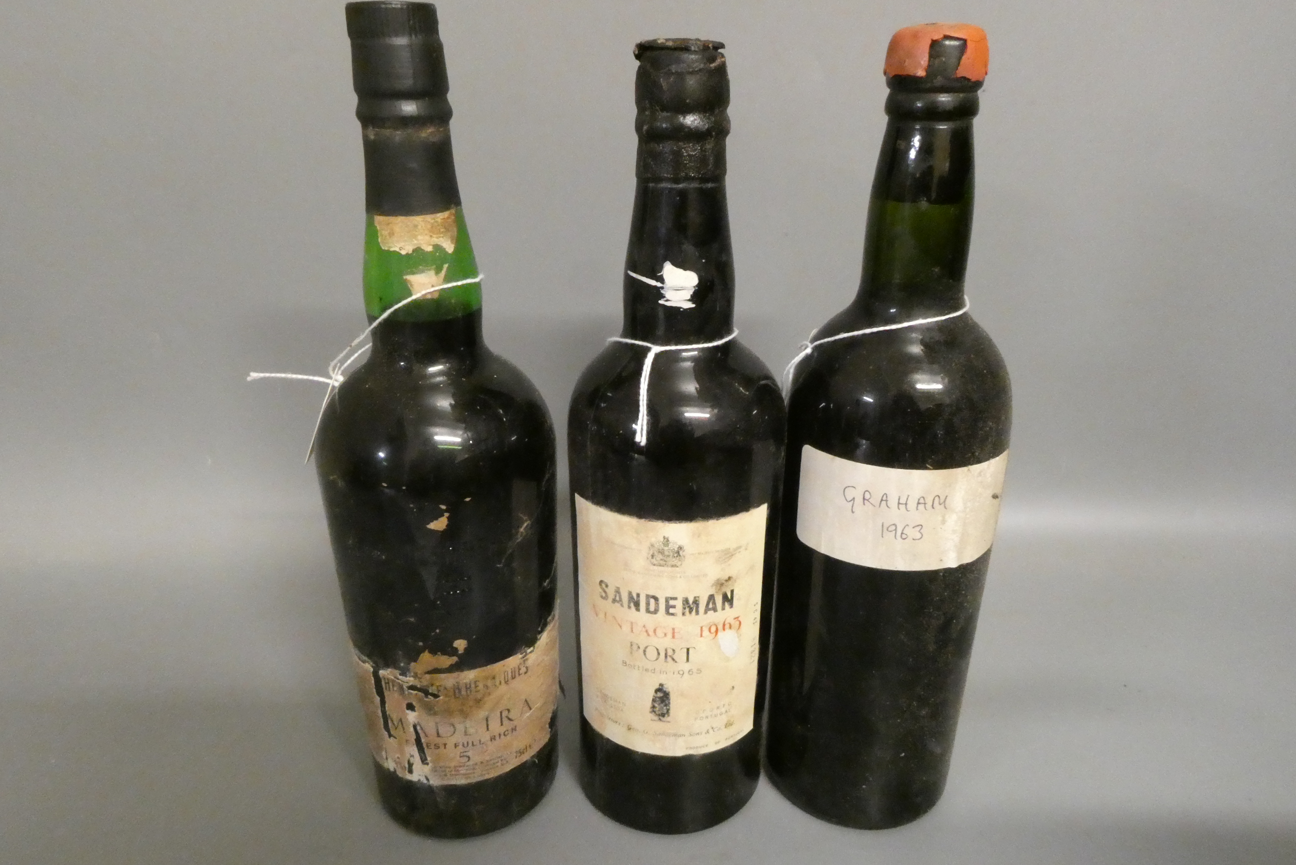 Two bottles of 1963 vintage port, comprising a Sandeman and a Graham's, together with a Henriques Image