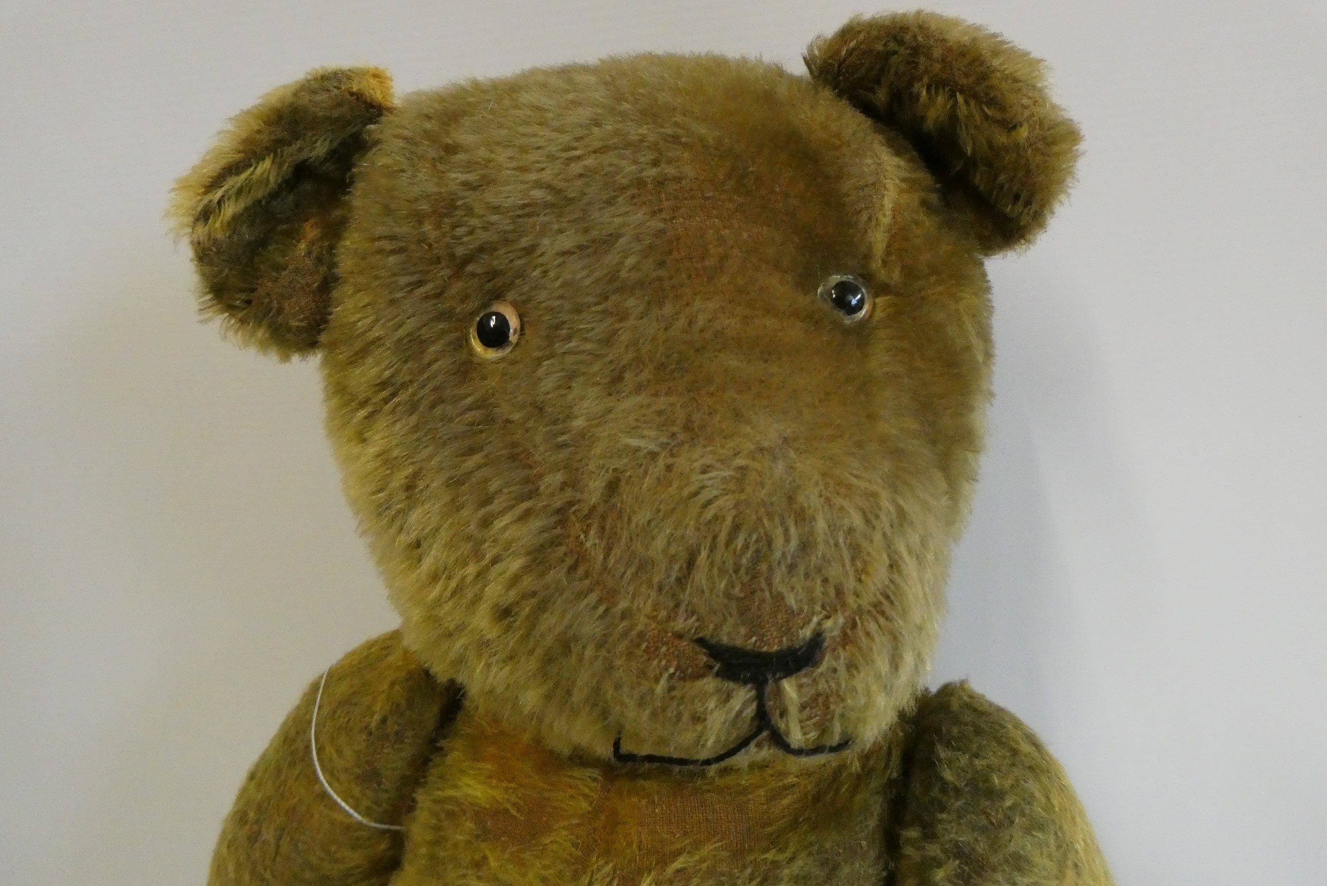 Pre-war jointed teddy bear, with clear glass eyes, orange plush sewn nose and felt pads, 26" long Image