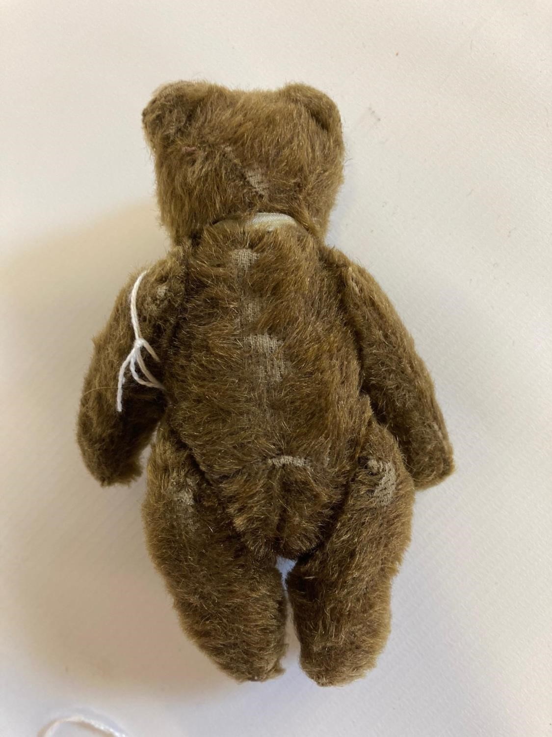 Small Steiff jointed bear, with glass eyes, brown plush, fabric bow and white metal ear button, 5 Image