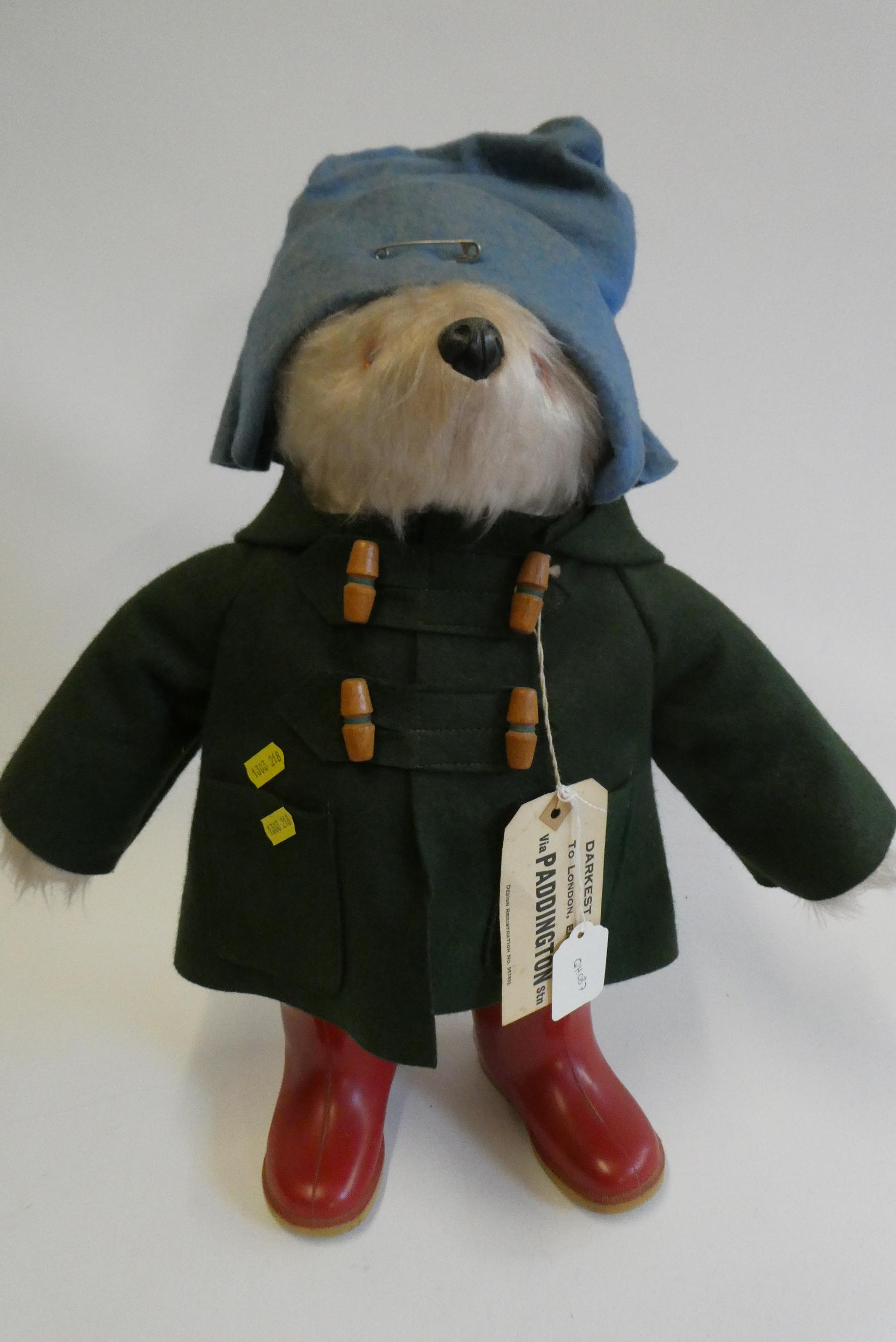 Paddington bear, with amber eyes, green felt coat, blue felt hat, red Dunlop boots, and card label, Image