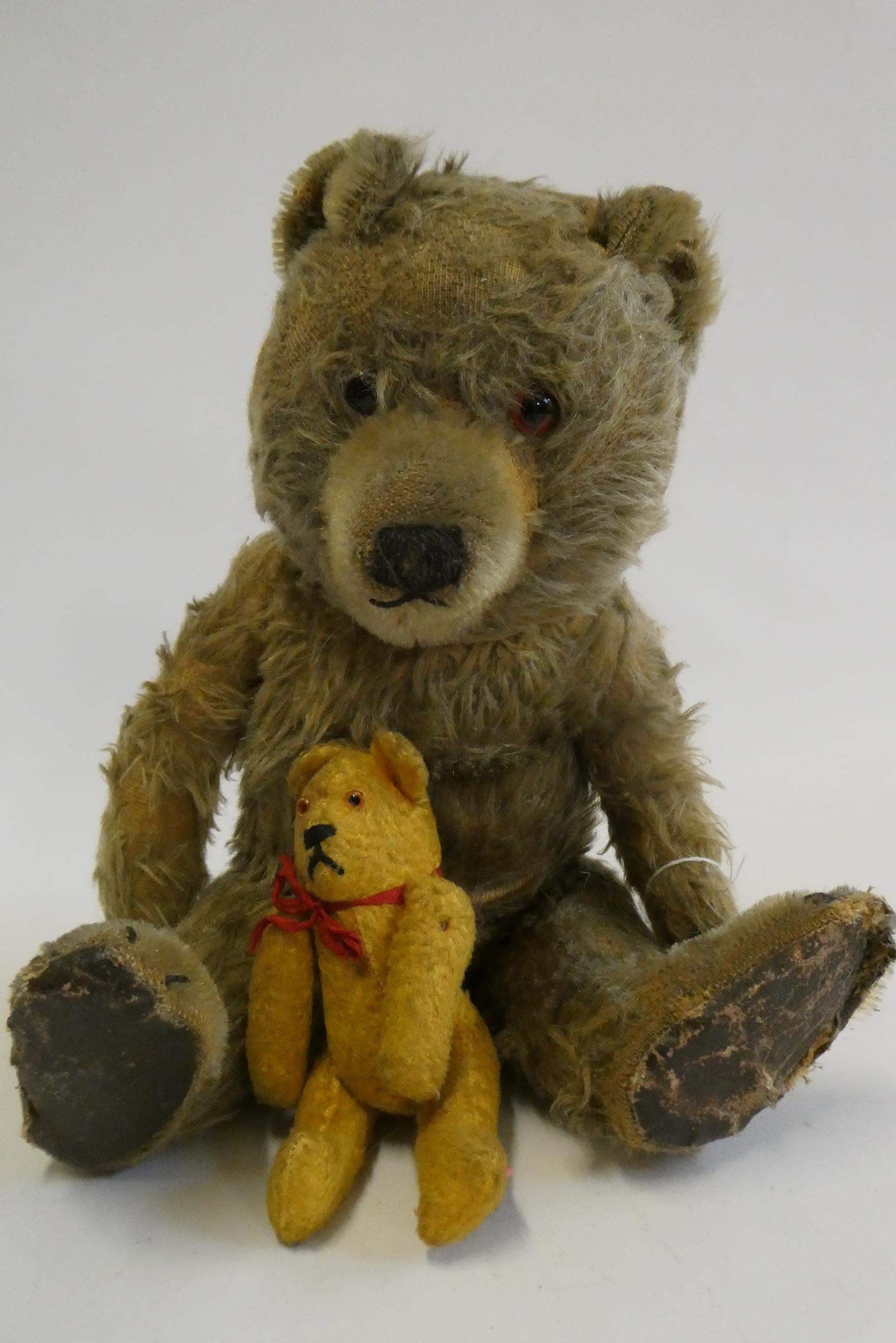 Two vintage bears, comprising a 13" bear with amber eyes and sewn nose, and a 5 1/4" orange soldier Image