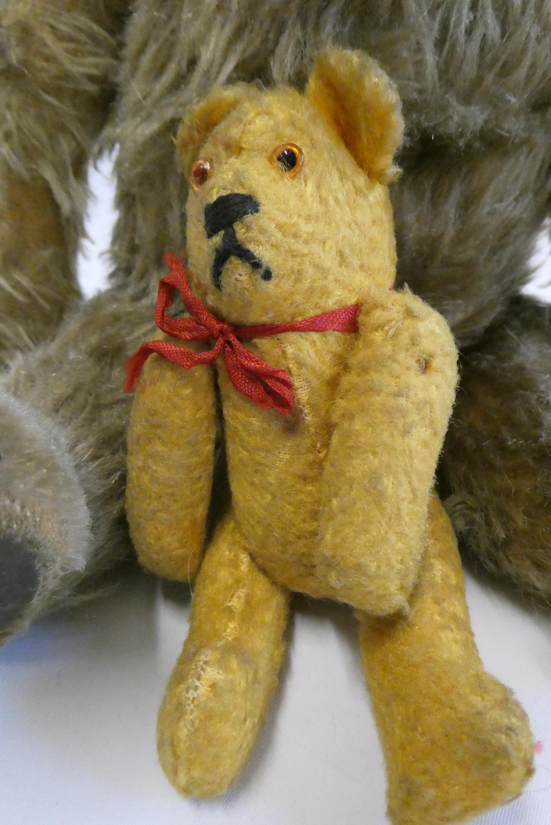 Two vintage bears, comprising a 13" bear with amber eyes and sewn nose, and a 5 1/4" orange soldier Image