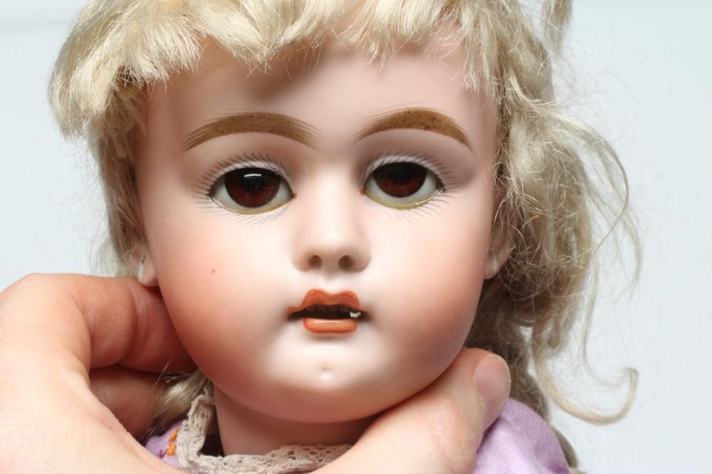 A bisque socket head doll, c.1900, with brown glass sleeping eyes, open mouth, teeth, pierced ears, Image
