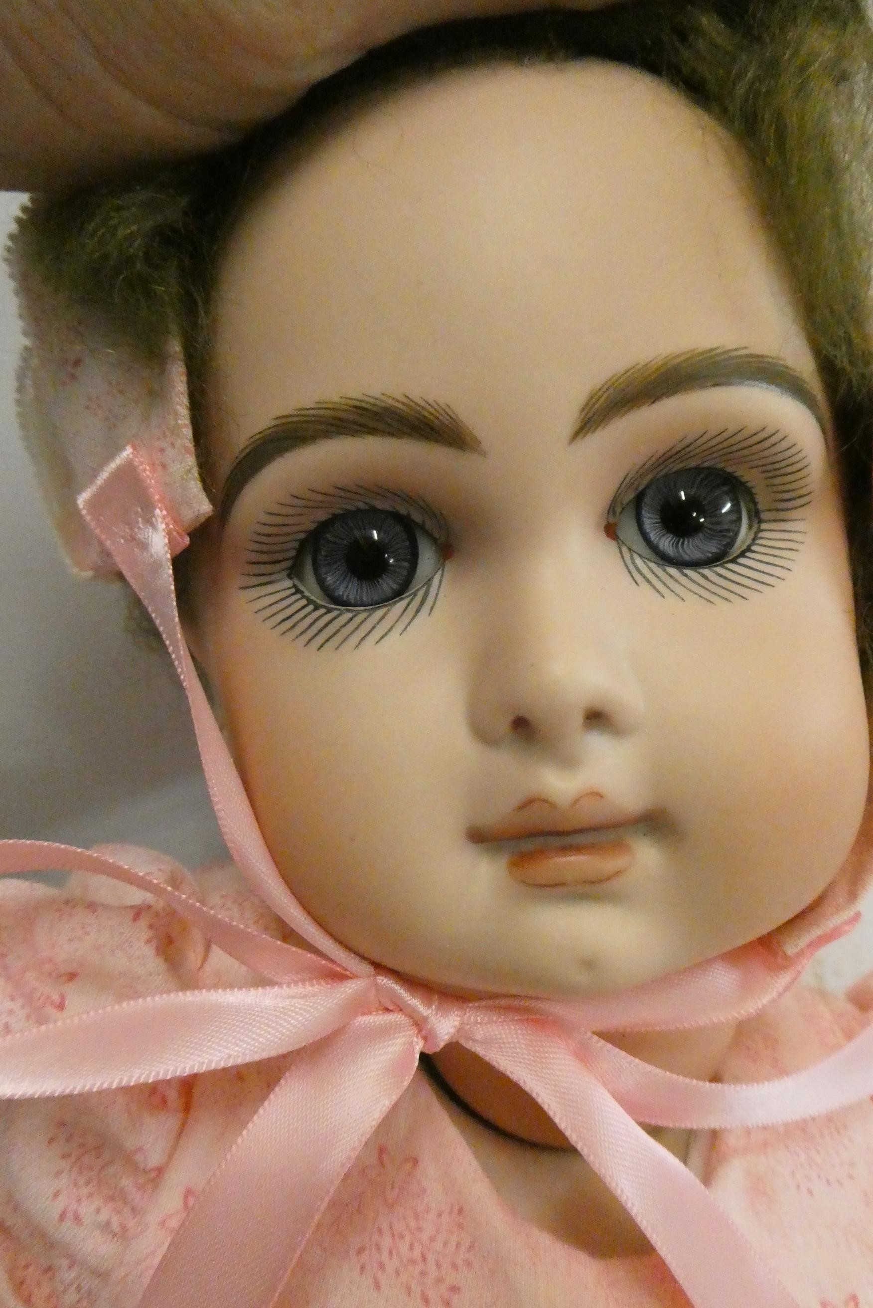A reproduction "Jumeau" bisque socket head doll, with blue glass fixed eyes, closed mouth, pierced Image