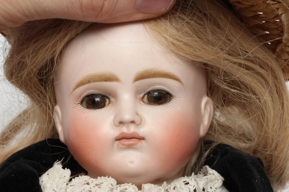 A Belton type bisque shoulder head doll, with brown glass eyes, closed mouth, blond wig, kid body, Image