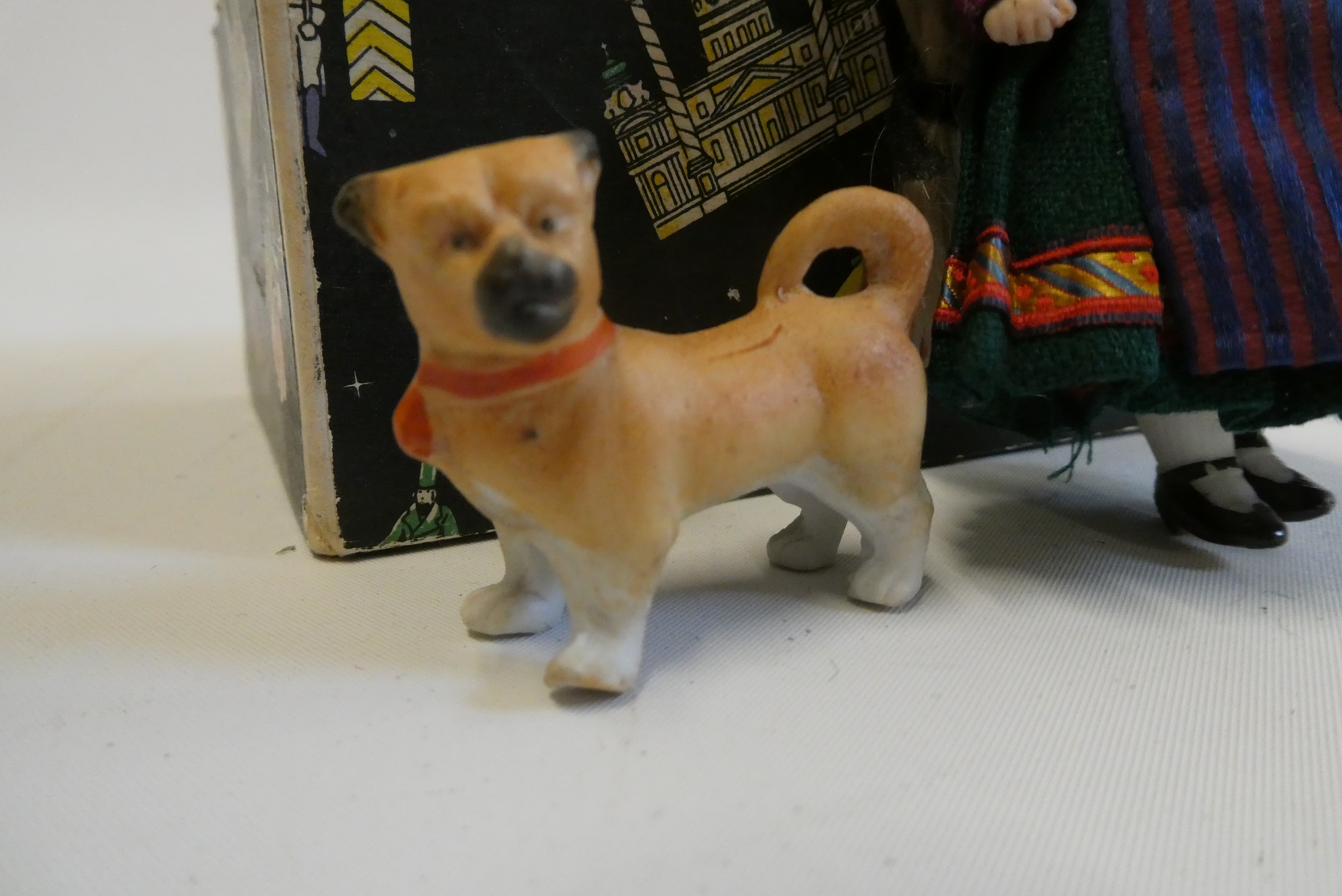 An all bisque dolls house doll, with brown glass fixed eyes, blond wig, straight legs, moulded shoes Image