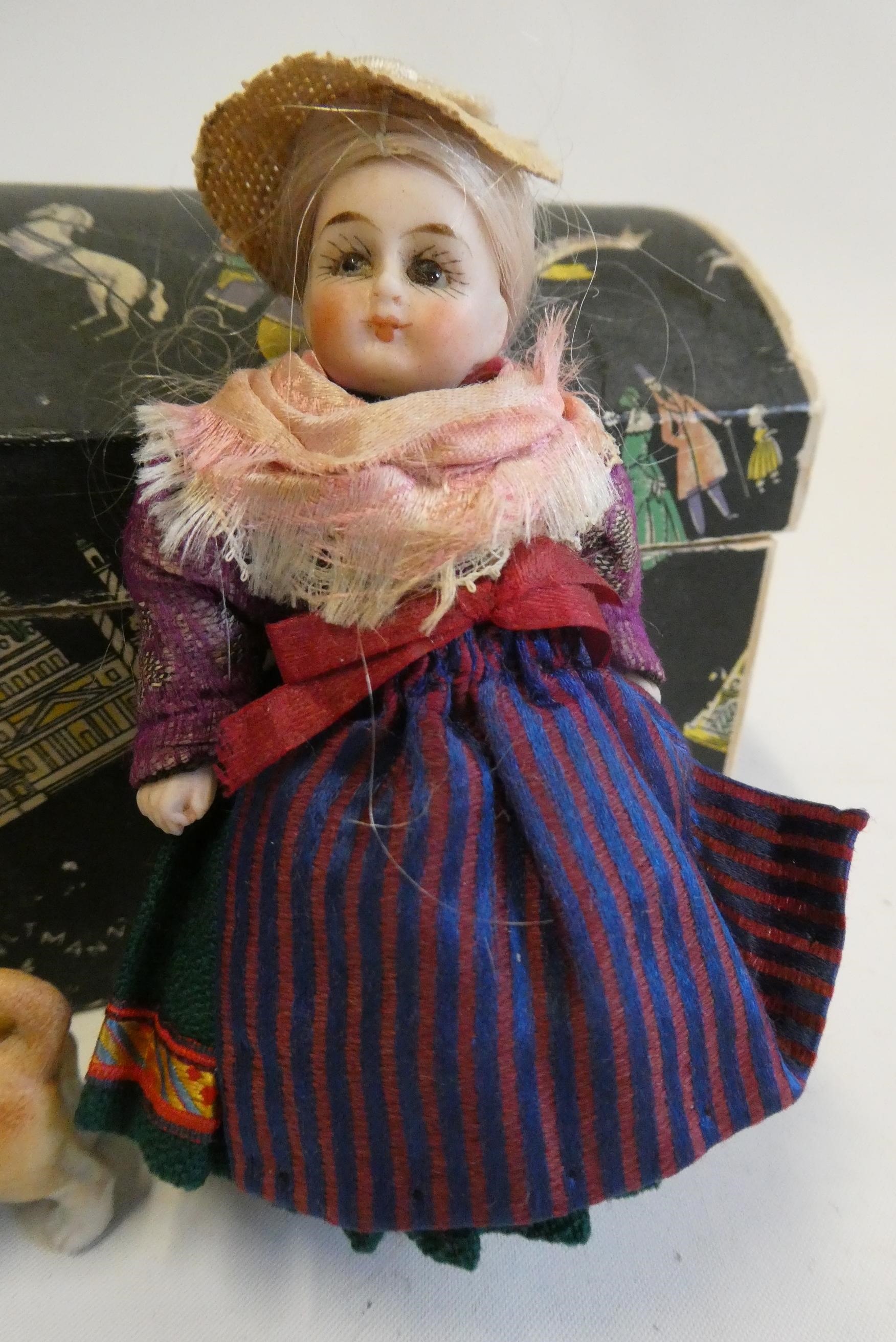 An all bisque dolls house doll, with brown glass fixed eyes, blond wig, straight legs, moulded shoes Image