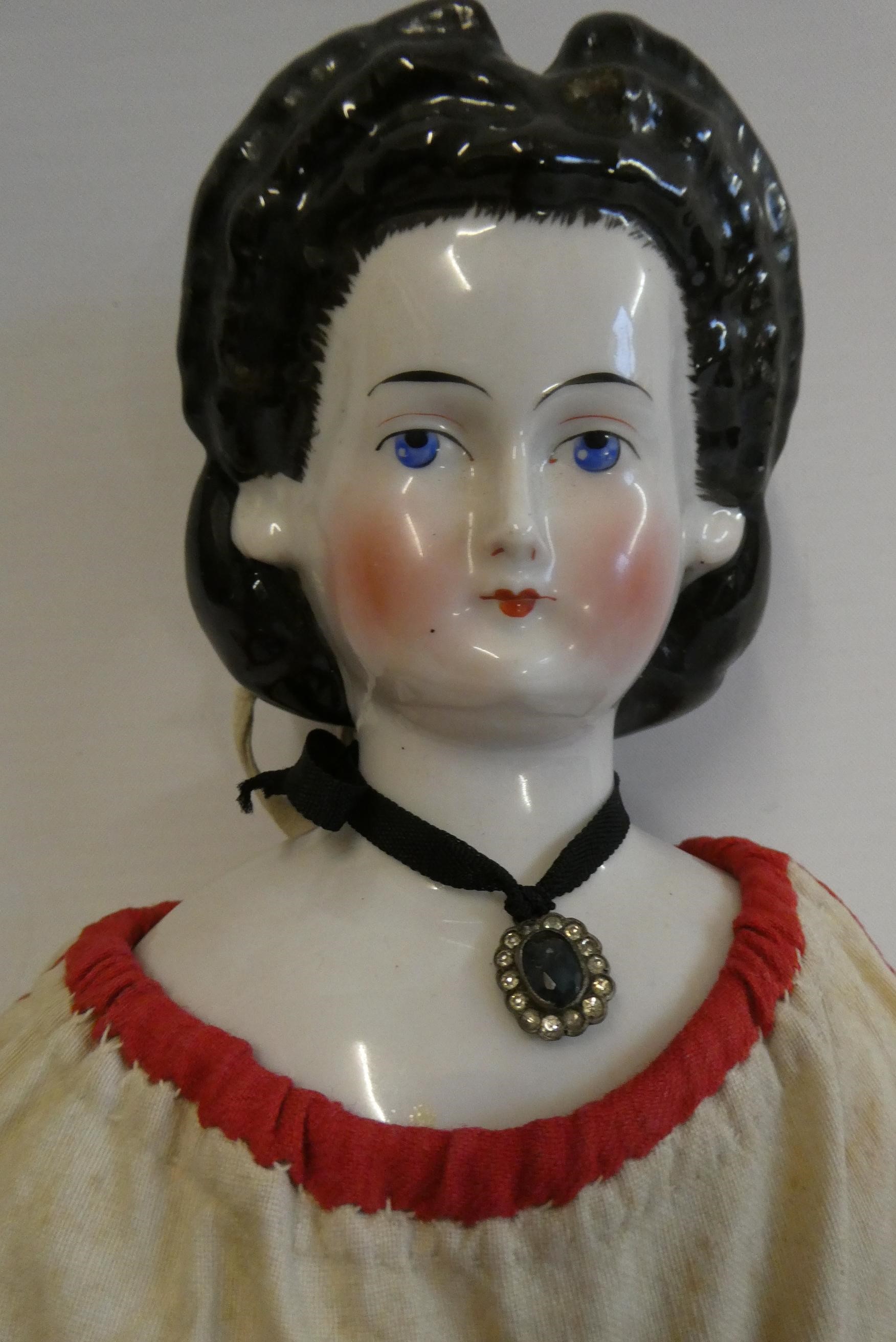 A china shoulder head doll, c.1880, with moulded hair, painted features, china lower limbs, moulded Image
