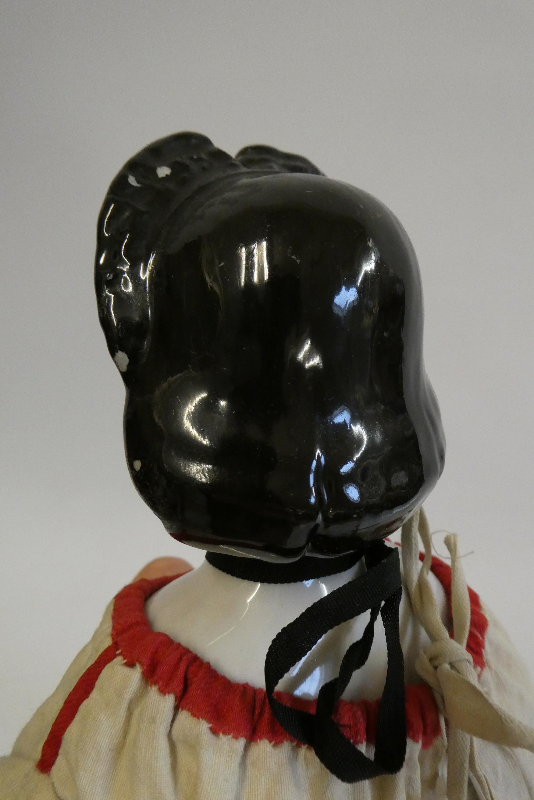 A china shoulder head doll, c.1880, with moulded hair, painted features, china lower limbs, moulded Image