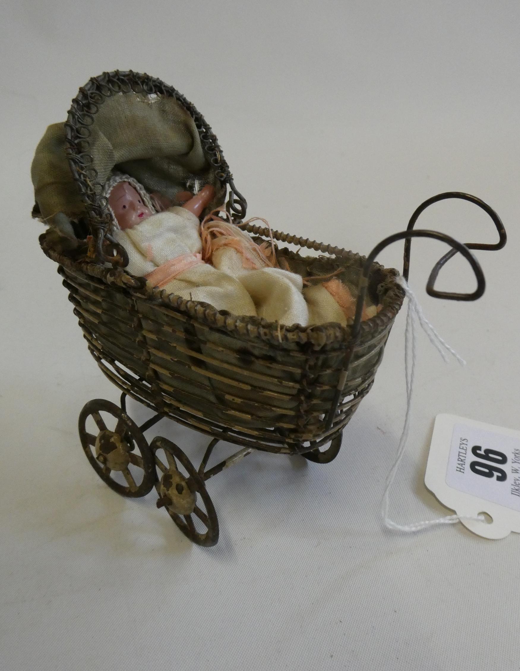 A pre-war filigree dolls house pram, with fabric hood and liner, 4 1/2" long, together with a Image