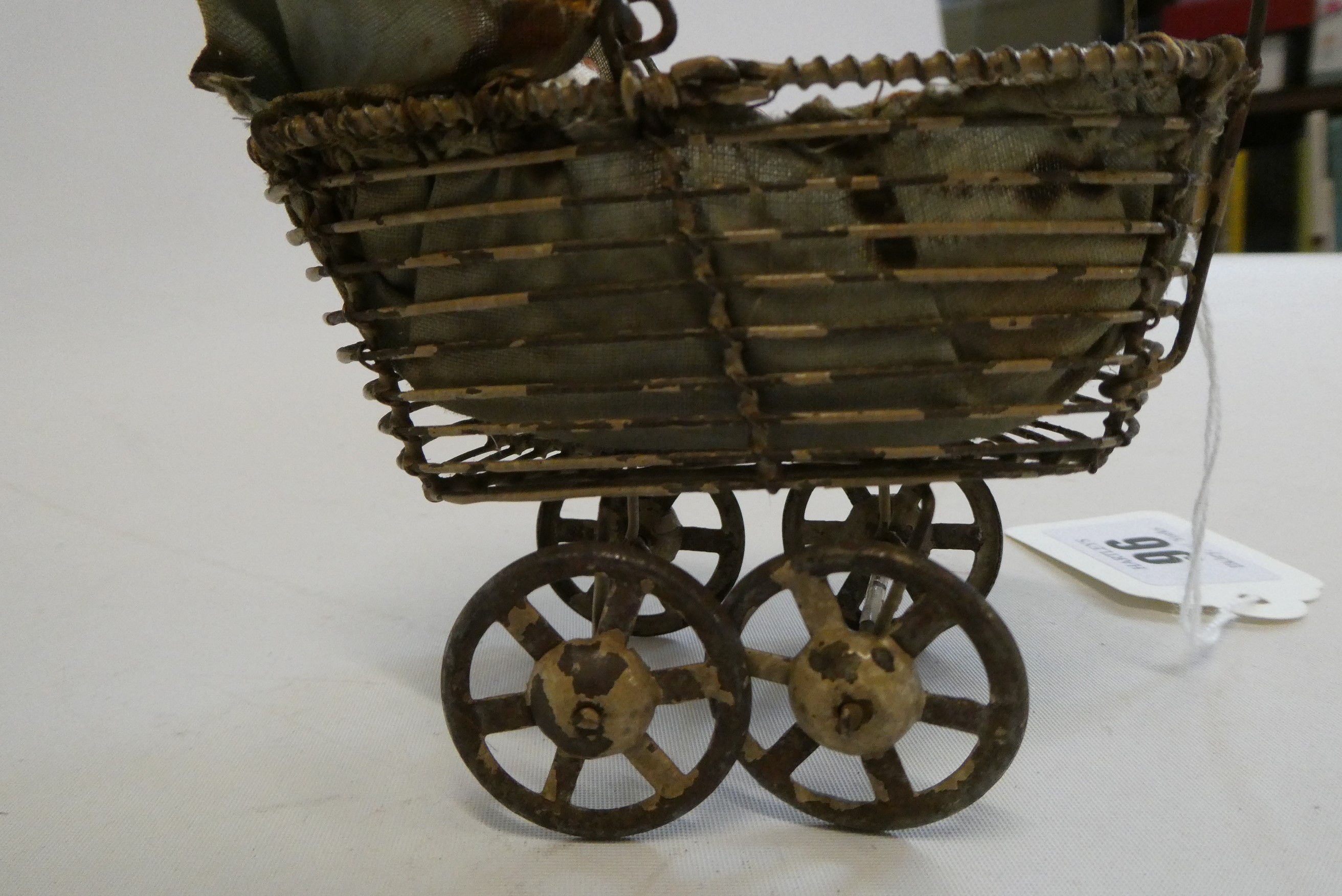 A pre-war filigree dolls house pram, with fabric hood and liner, 4 1/2" long, together with a Image