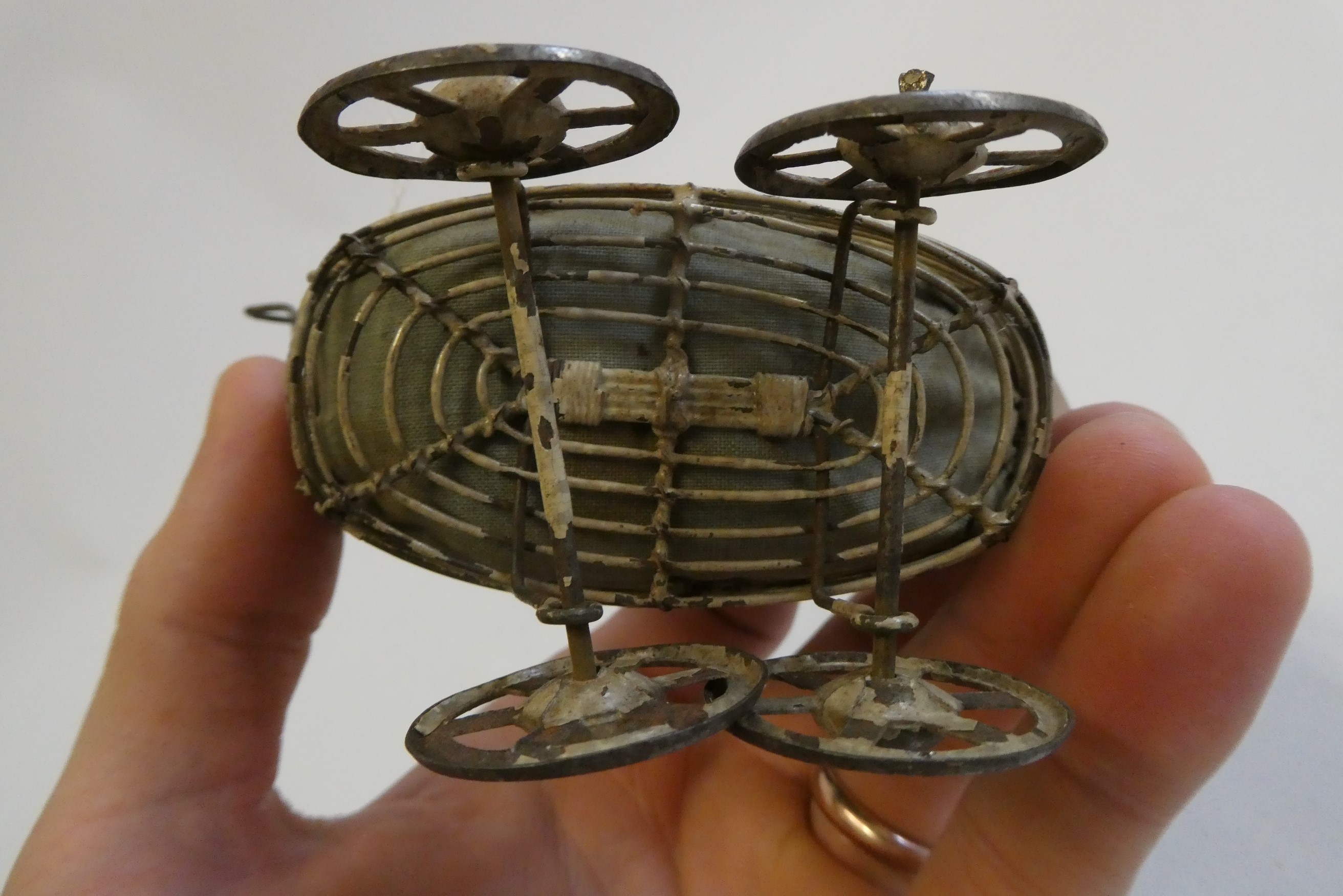 A pre-war filigree dolls house pram, with fabric hood and liner, 4 1/2" long, together with a Image