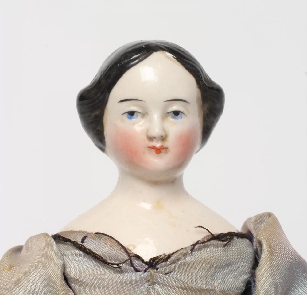 A china shoulder head doll, c.1880, with moulded hair, painted features, fabric body, china lower Image