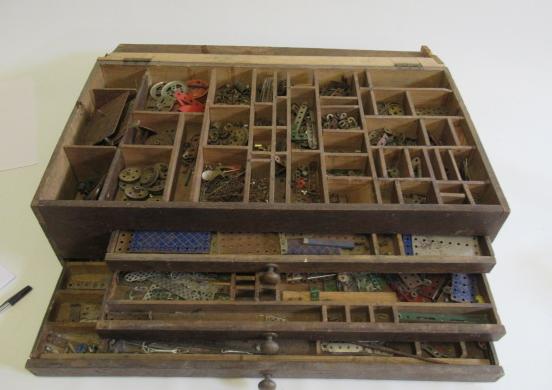 A wooden box with tray and three drawers containing mainly blue and silver Meccano parts Image