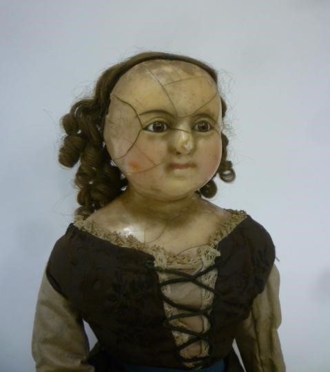 A wax shoulder head doll with fixed brown glass eyes Image