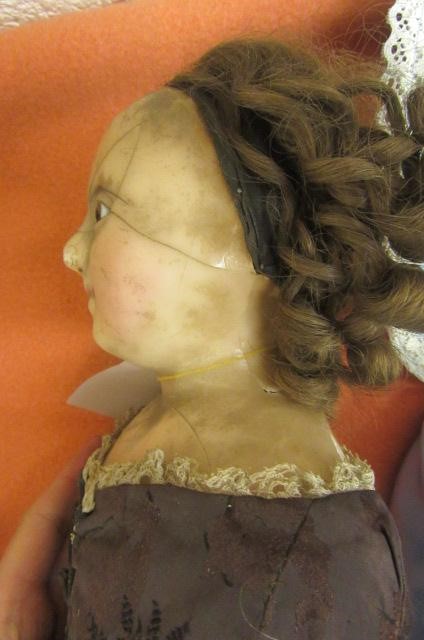 A wax shoulder head doll with fixed brown glass eyes Image