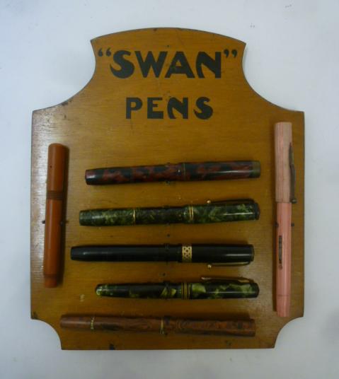 A "Swan Pens" wood easel display stand with seven fountain pen outers Image
