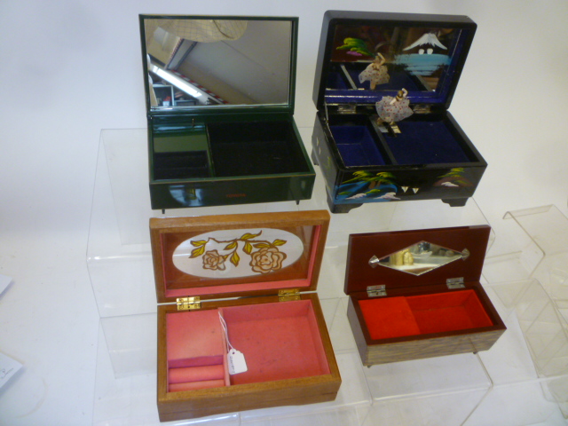 Four musical jewel boxes comprising a black lacquered and painted wood box with dancing lady Image
