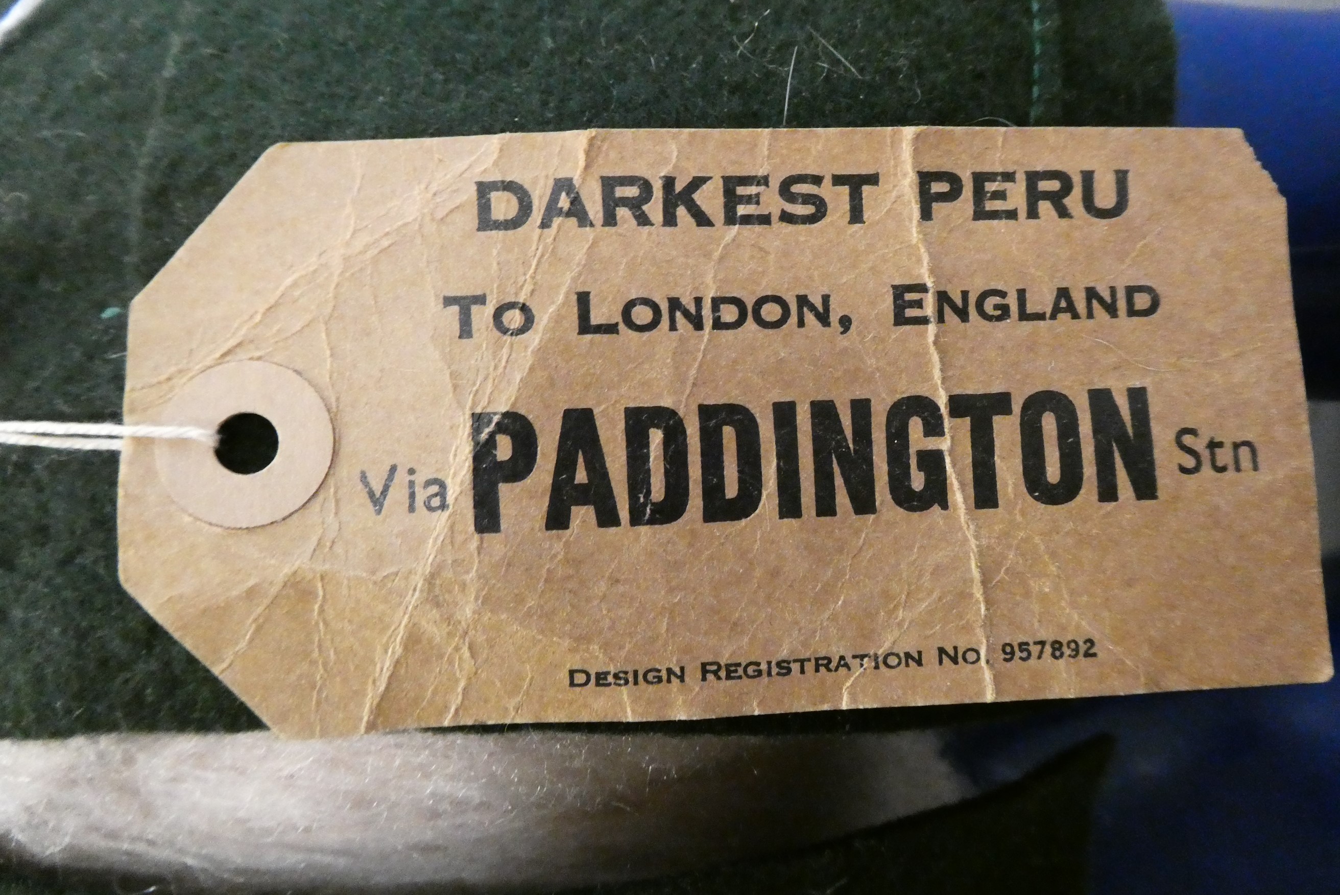 Vintage Paddington bear, with orange felt hat, green felt coat, blue Dunlop boots and cardboard Image