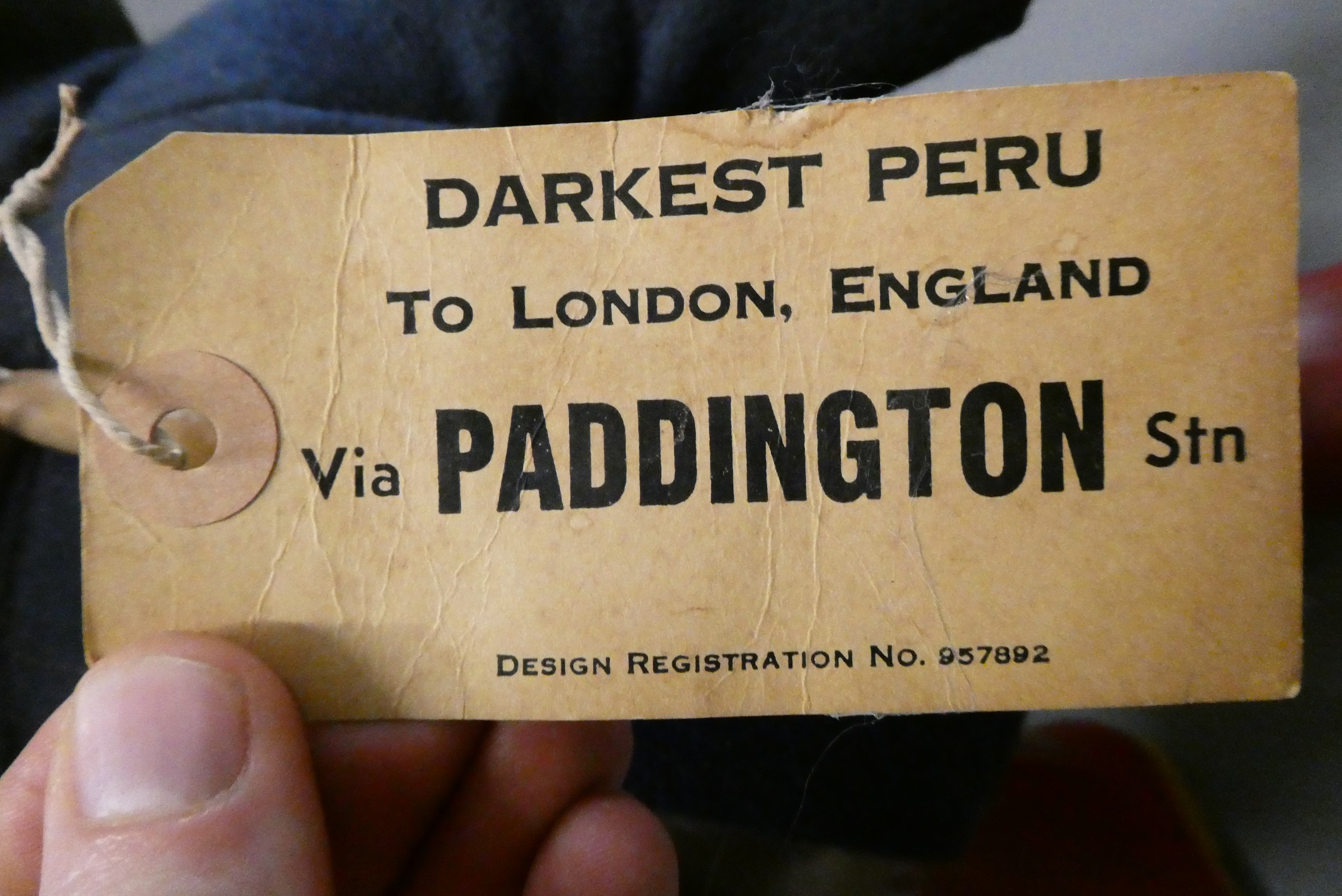 Vintage Paddington bear, with light blue felt hat, blue felt coat, red Dunlop boots and cardboard Image