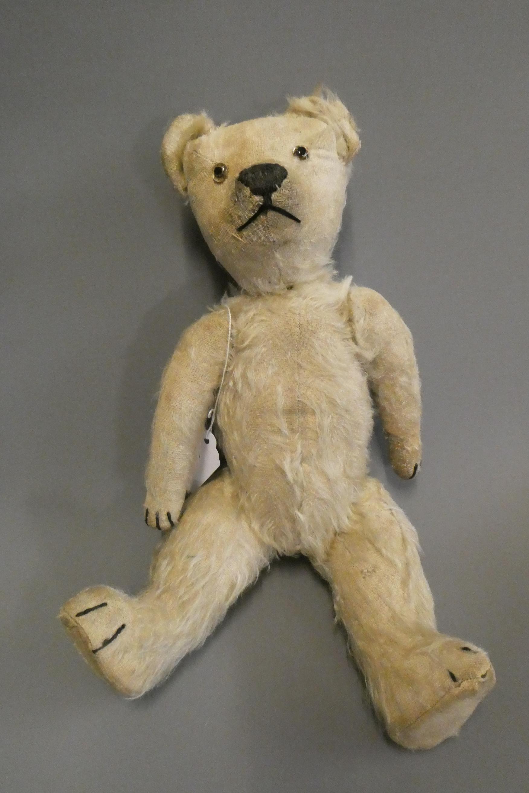 A Chad Valley cork filled teddy bear, circa 1920, with clear glass eyes, white plush, sewn nose and Image