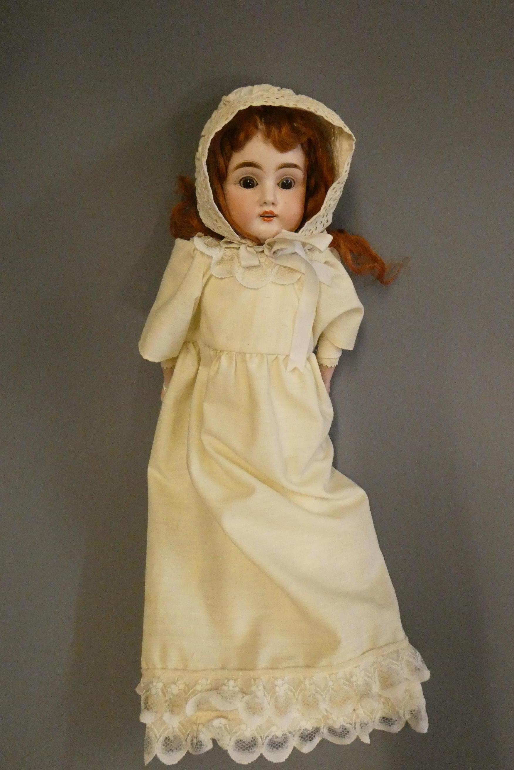 A bisque shoulder head doll, with brown glass sleeping eyes, open mouth, teeth, auburn wig, kid Image