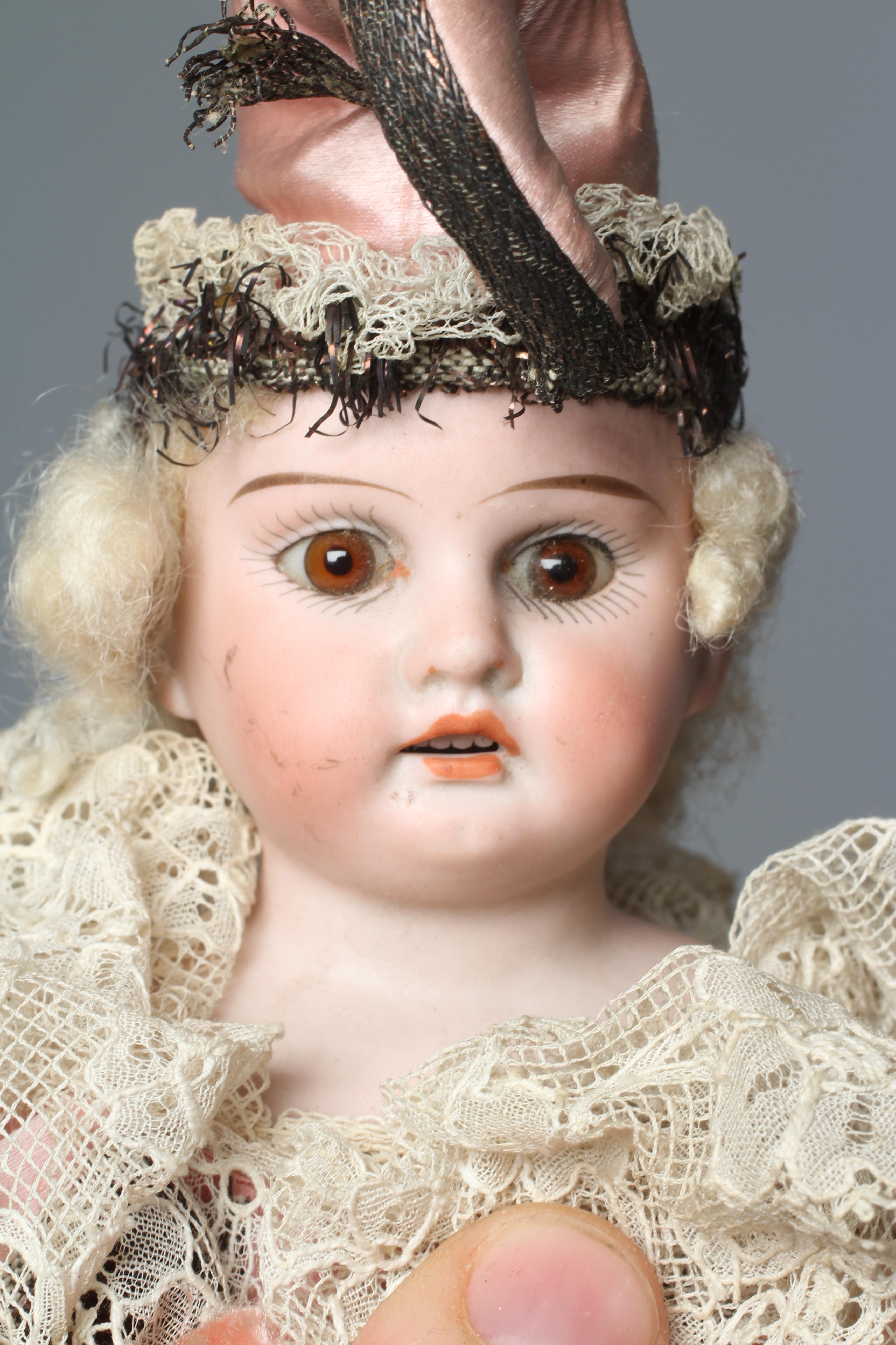 An Armand Marseille bisque shoulder head Marotte doll, with brown glass fixed eyes, open mouth Image