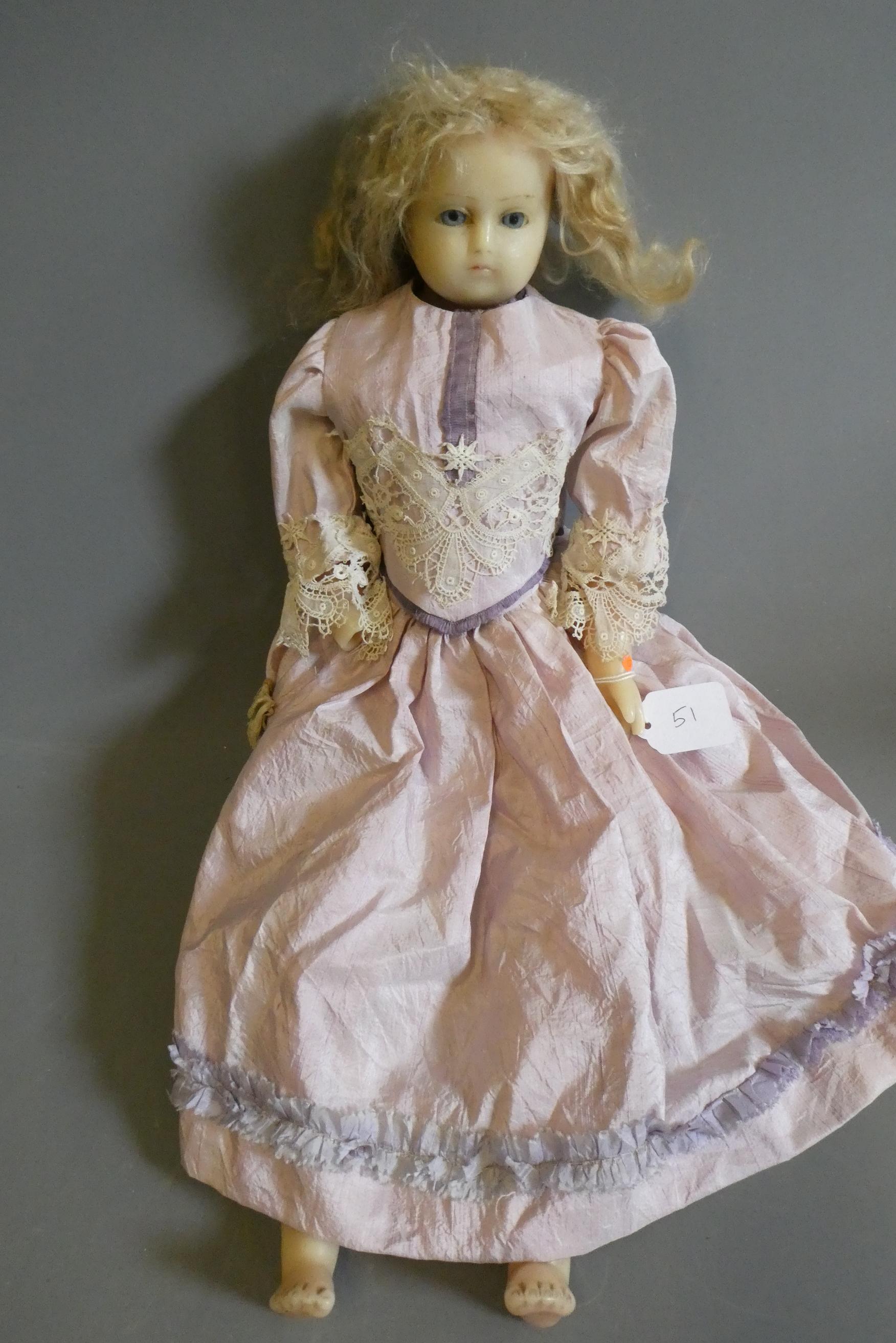 A Victorian wax shoulder head doll, with blue glass fixed eyes, moulded closed mouth, fabric body Image