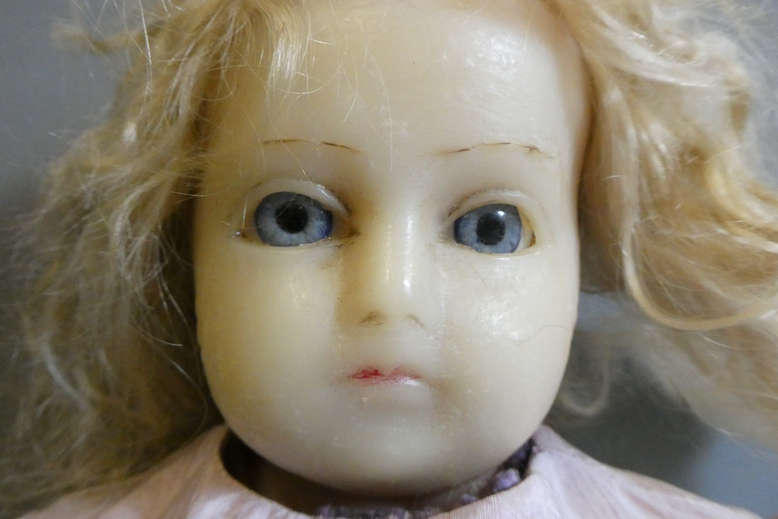 A Victorian wax shoulder head doll, with blue glass fixed eyes, moulded closed mouth, fabric body Image