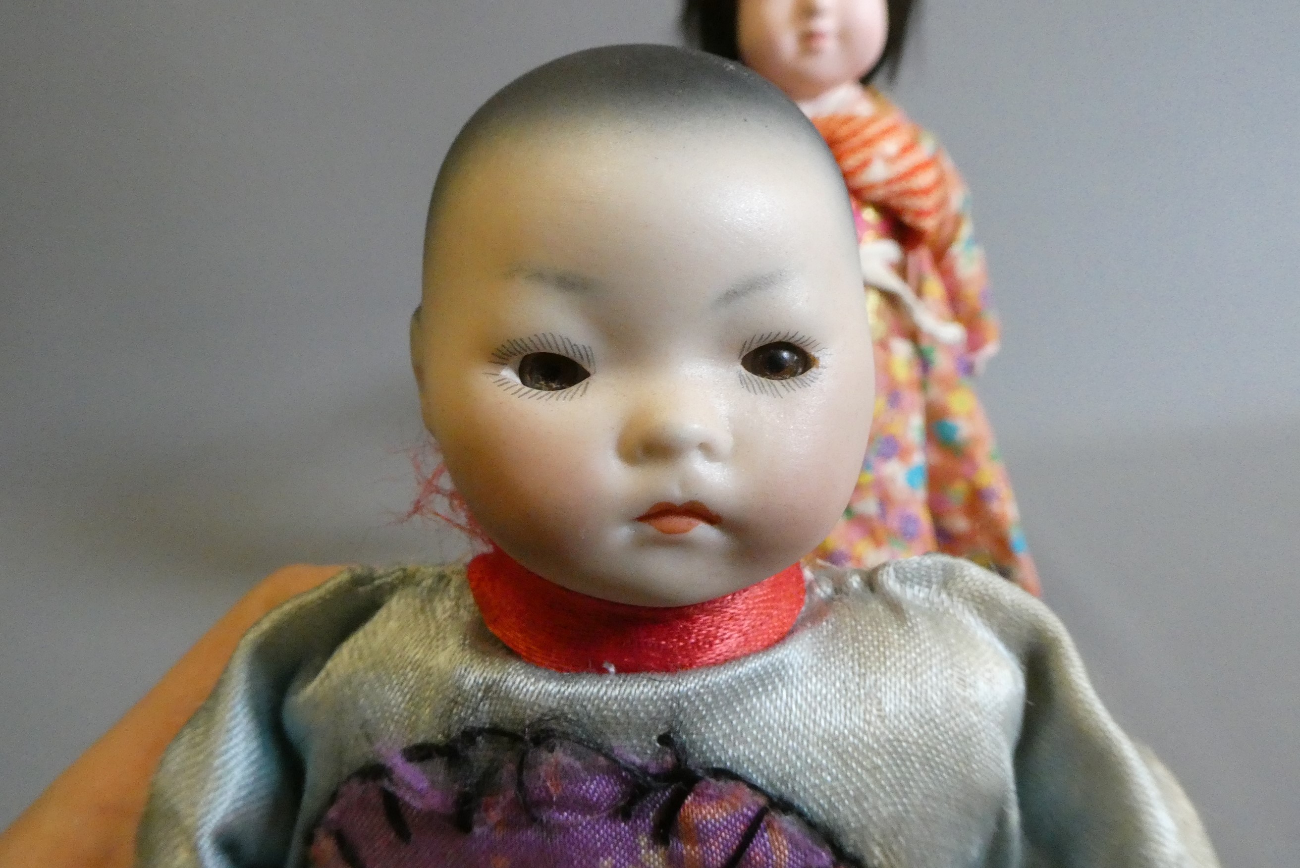 Two oriental dolls comprising an 11" bisque flange neck boy with sleeping eyes Image
