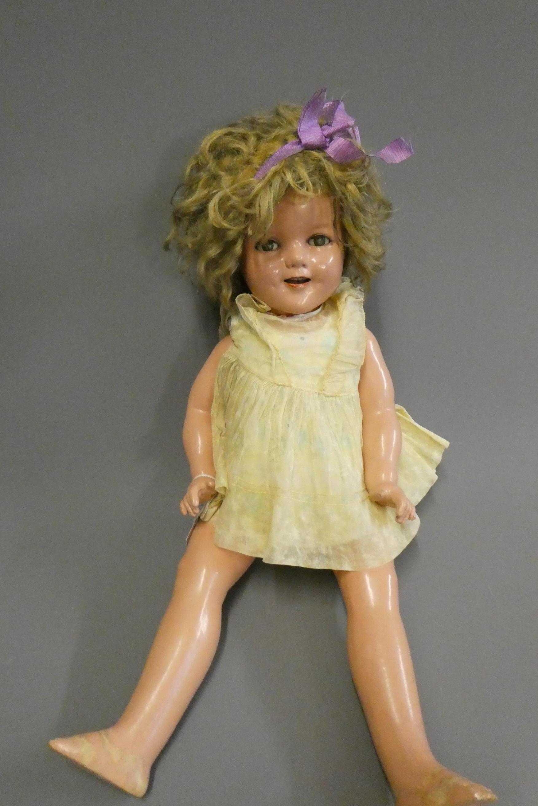 A Shirley Temple doll, with blue sleeping eyes, open mouth, teeth, blond wig, jointed composition Image