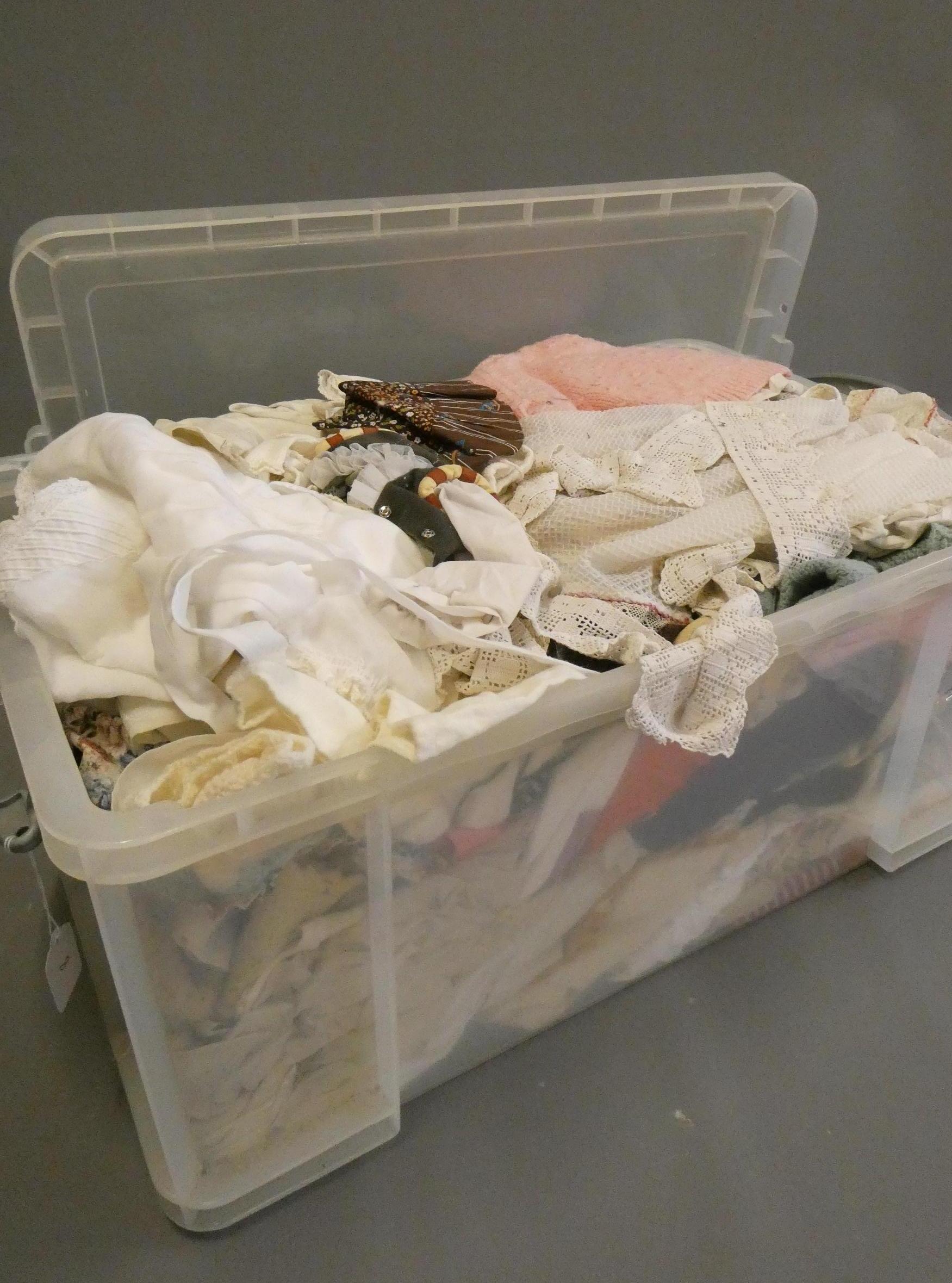 A large box of mixed dolls clothes, in varied sizes Image