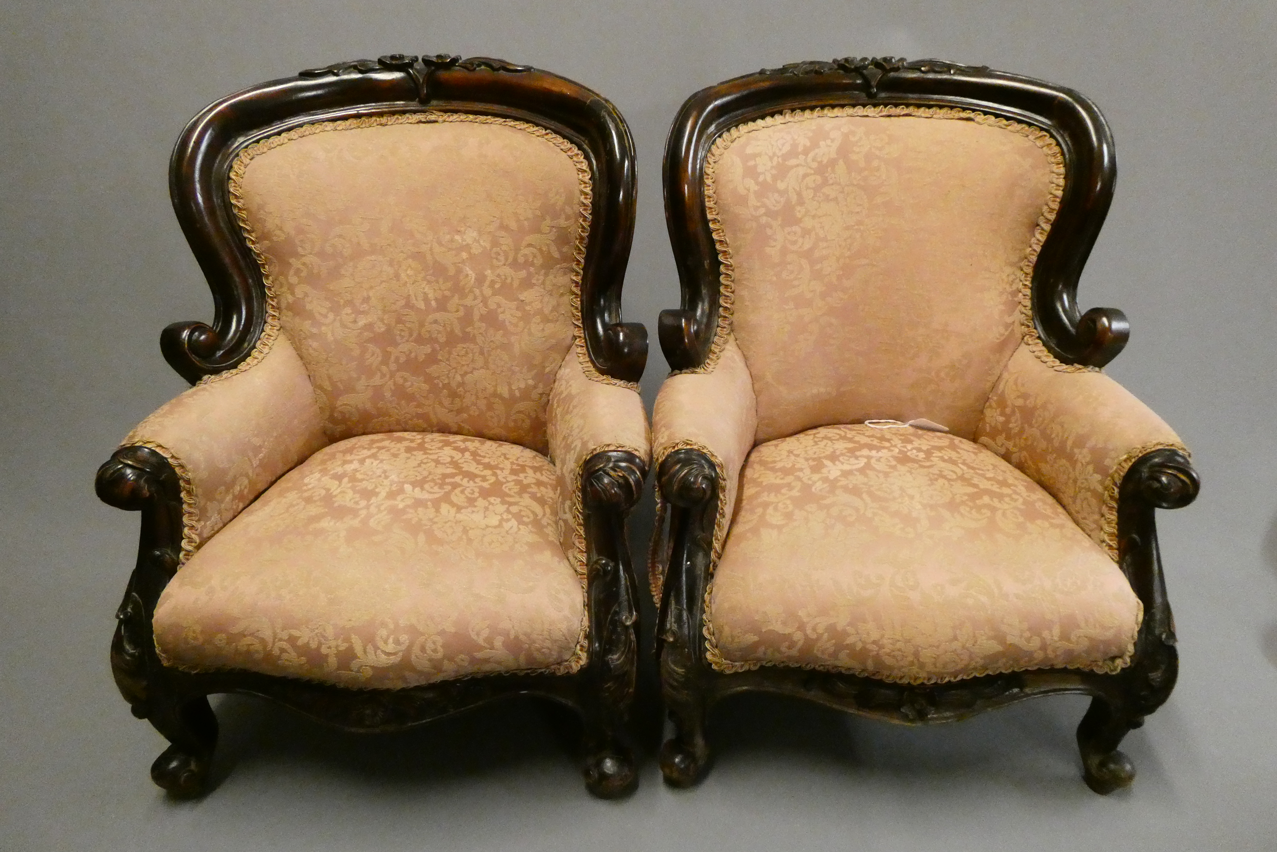 A pair of French style doll's chairs with carved wood frames, scroll arms and pink floral Image