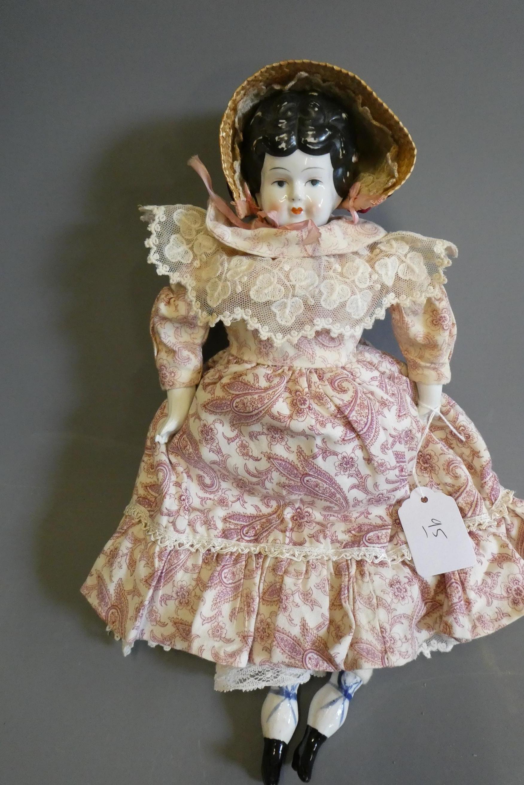 A Victorian china shoulder head doll, with moulded hair, painted features, fabric body, china lower Image