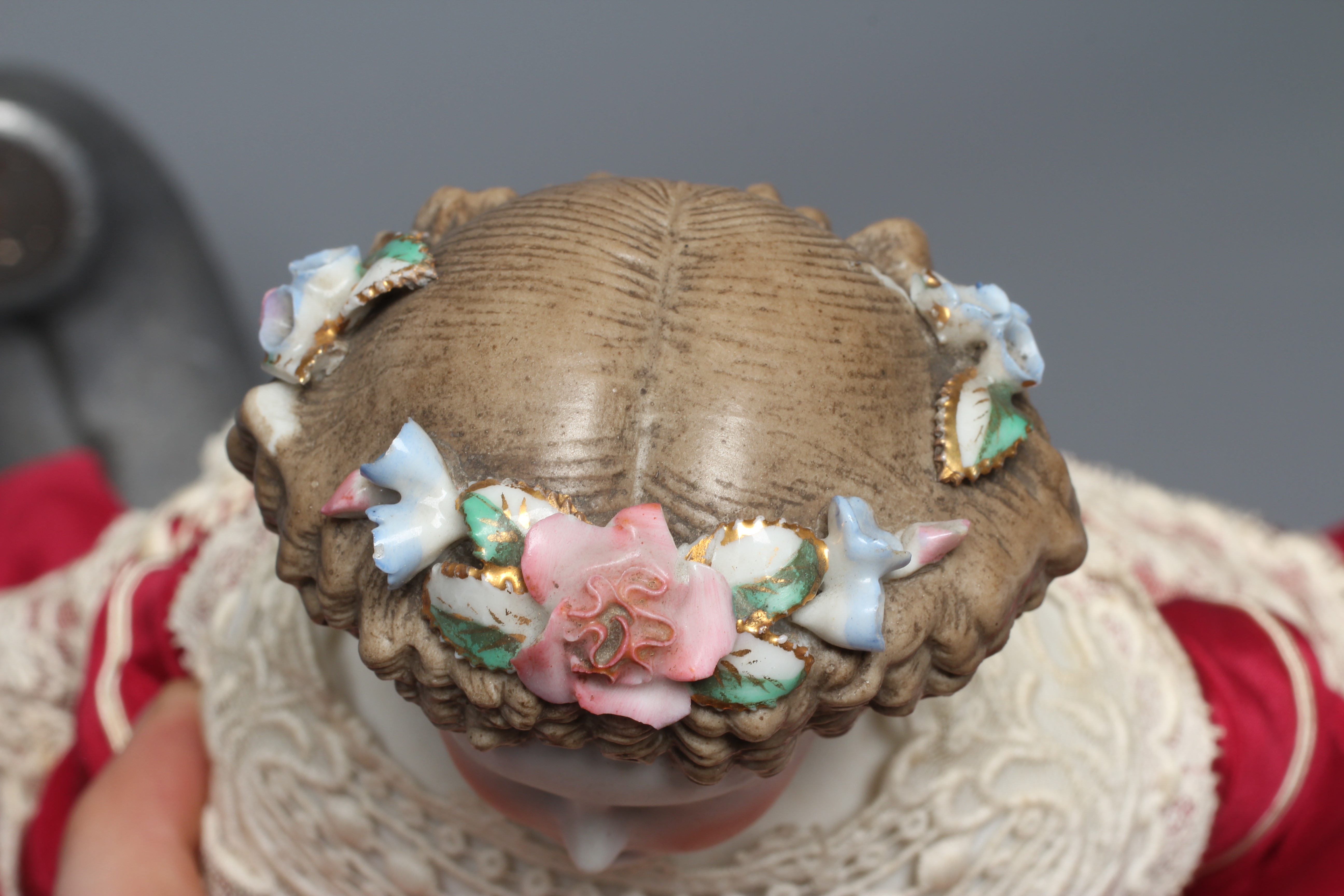 A bisque shoulder head doll, possibly Dornheim, with moulded hair encrusted with flowers, painted Image
