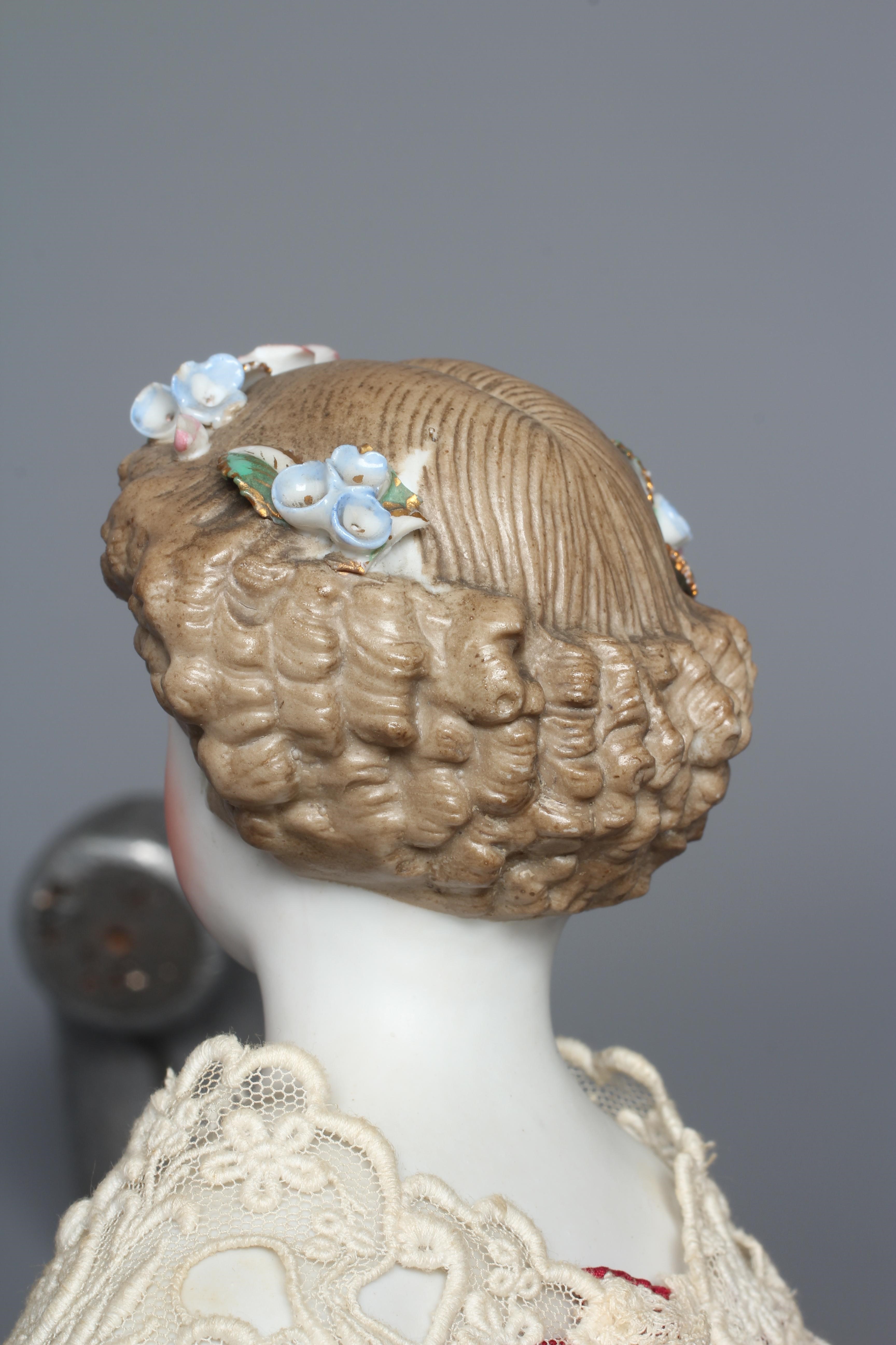 A bisque shoulder head doll, possibly Dornheim, with moulded hair encrusted with flowers, painted Image