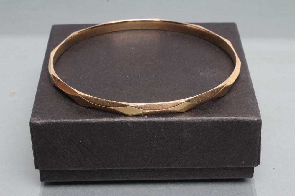 A 9CT GOLD BANGLE of faceted circular form Image