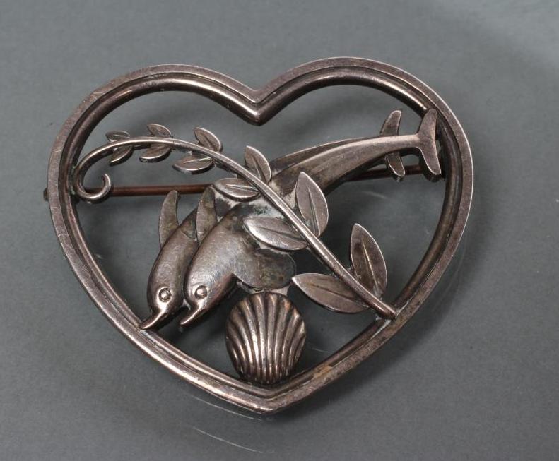 A GEORG JENSEN SILVER HEART BROOCH designed by Arno Molinowski as a pair of dolphins leaping over a Image