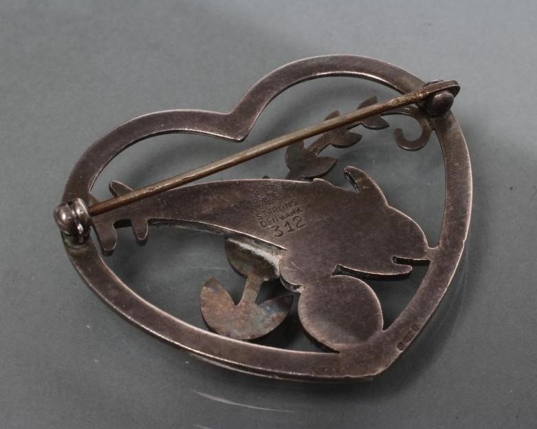 A GEORG JENSEN SILVER HEART BROOCH designed by Arno Molinowski as a pair of dolphins leaping over a Image