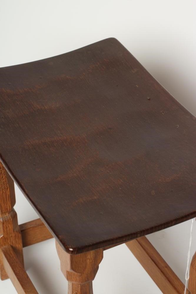 A ROBERT THOMPSON ADZED OAK STOOL of dished oblong form with faceted baluster turned and block legs Image