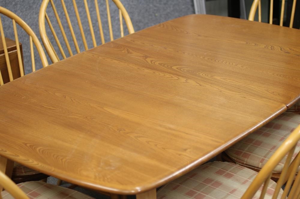 AN ERCOL WINDSOR BEECH AND ELM DINING SUITE comprising an extending table with rounded oblong top Image
