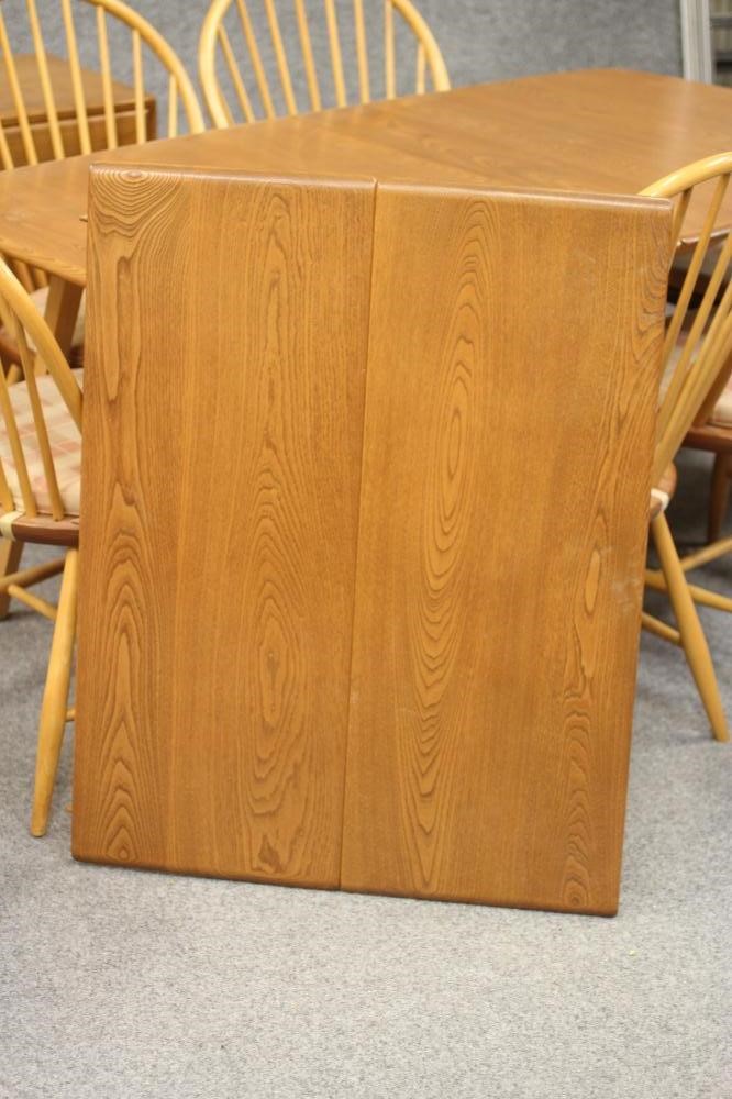 AN ERCOL WINDSOR BEECH AND ELM DINING SUITE comprising an extending table with rounded oblong top Image