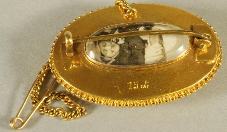 A VICTORIAN 15CT GOLD BROOCH of swept oval form with applied filigree work border Image