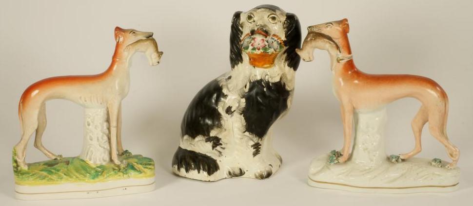 A VICTORIAN STAFFORDSHIRE POTTERY SPANIEL with black and white markings holding a basket of flowers Image