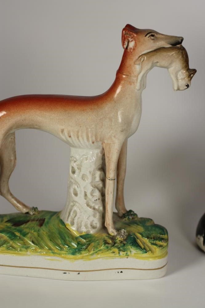 A VICTORIAN STAFFORDSHIRE POTTERY SPANIEL with black and white markings holding a basket of flowers Image