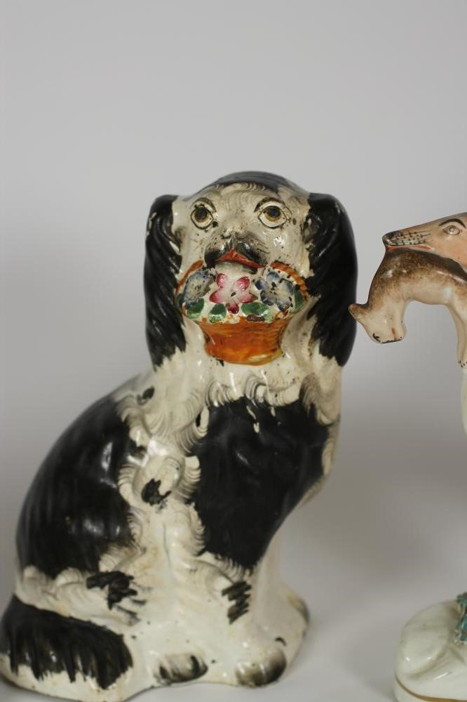 A VICTORIAN STAFFORDSHIRE POTTERY SPANIEL with black and white markings holding a basket of flowers Image
