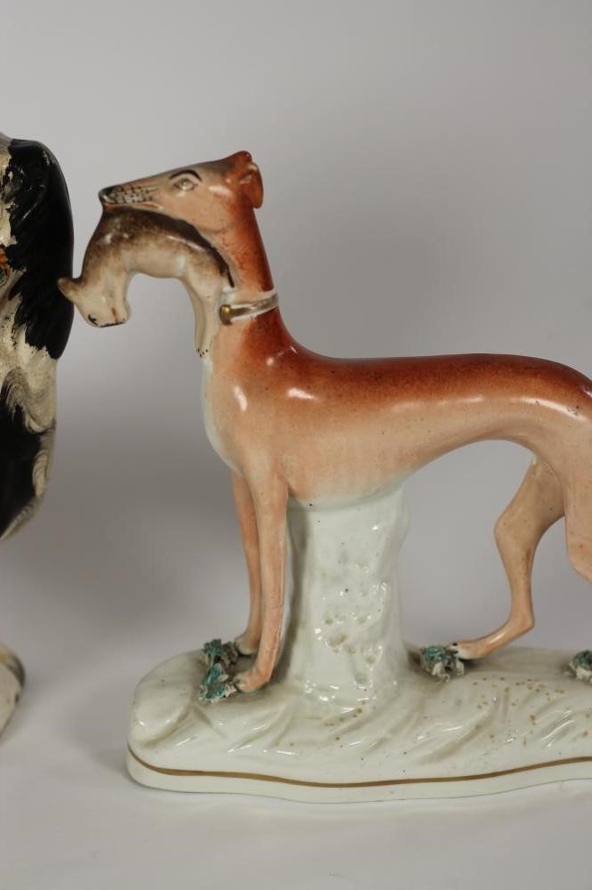 A VICTORIAN STAFFORDSHIRE POTTERY SPANIEL with black and white markings holding a basket of flowers Image