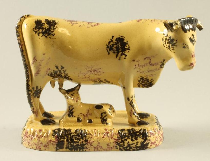AN ENGLISH BUFF GLAZED EARTHENWARE MODEL OF A COW AND CALF Image