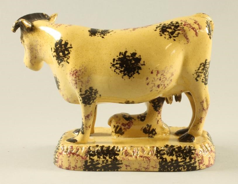 AN ENGLISH BUFF GLAZED EARTHENWARE MODEL OF A COW AND CALF Image