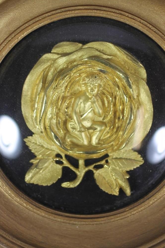A VICTORIAN ORMOLU SMALL PLAQUE cast as a cupid kneeling within a full blown rose Image